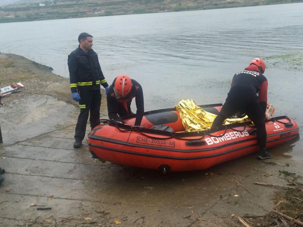 Los bomberos llegan a tierra con el cadáver del pescador ahogado en el embalse de Ribarroja.