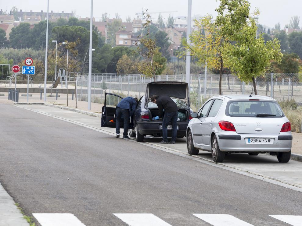 Dos agentes inspeccionando el coche donde fue hallado el herido en la calle Cruz del Sur.