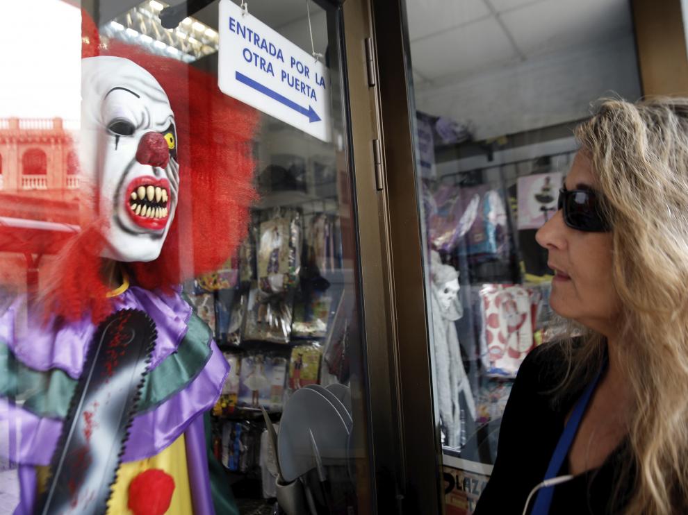 Una mujer observa un dizfraz de payaso diabólico expuesto en una tienda valenciana