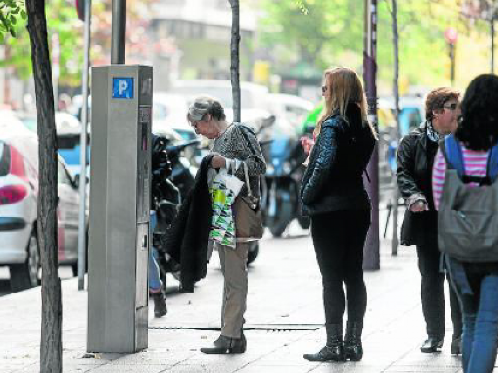 Una mujer paga en un parquímetro, en el centro de Zaragoza.