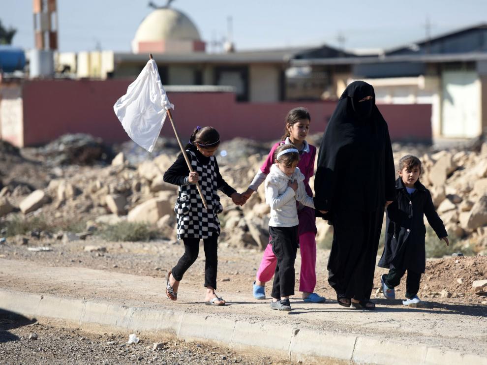 Una mujer y varios niños intentan dejar Mosul alzando una bandera blanca.