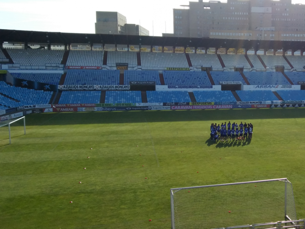 La plantilla del Real Zaragoza, en el habitual corro incial, antes del inicio del entrenamiento de este sábado en La Romareda.