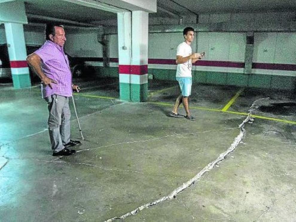 Varios vecinos del edificio afectado, junto a la enorme grieta que se abrió en el garaje.