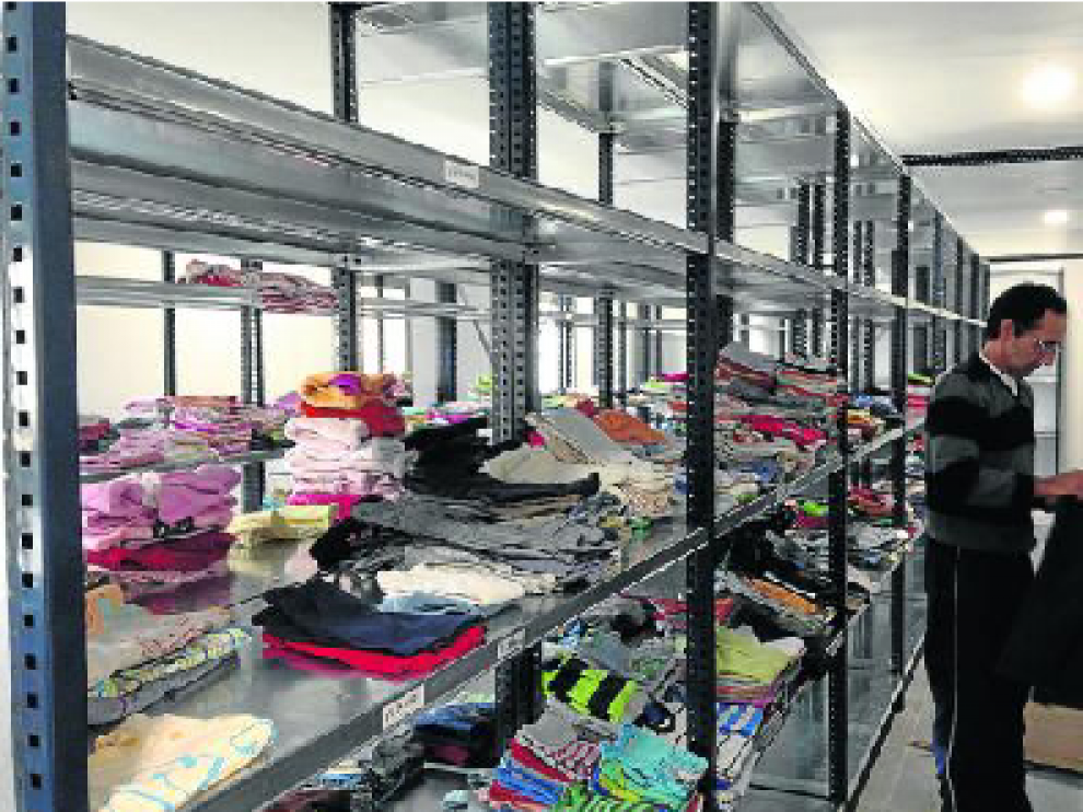 Un voluntario, junto a las estanterías donde se guarda la ropa que luego se distribuye.
