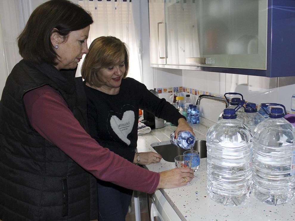 Las vecinas Cortés (izda.) y Martínez en la cocina, con agua embotellada.