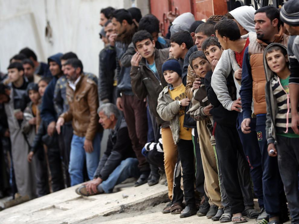 Cientos de iraquíes esperan para recibir comida en Mosul.