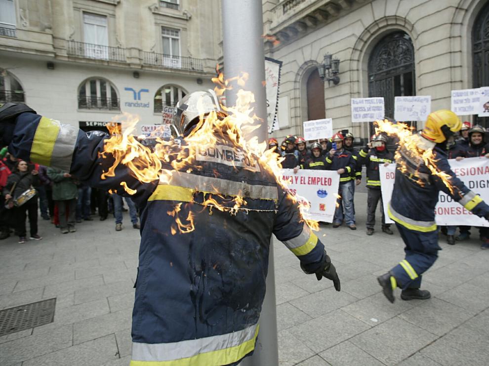 Dos bomberos, protegidos, han sido quemados por sus compañeros durante la concentración.