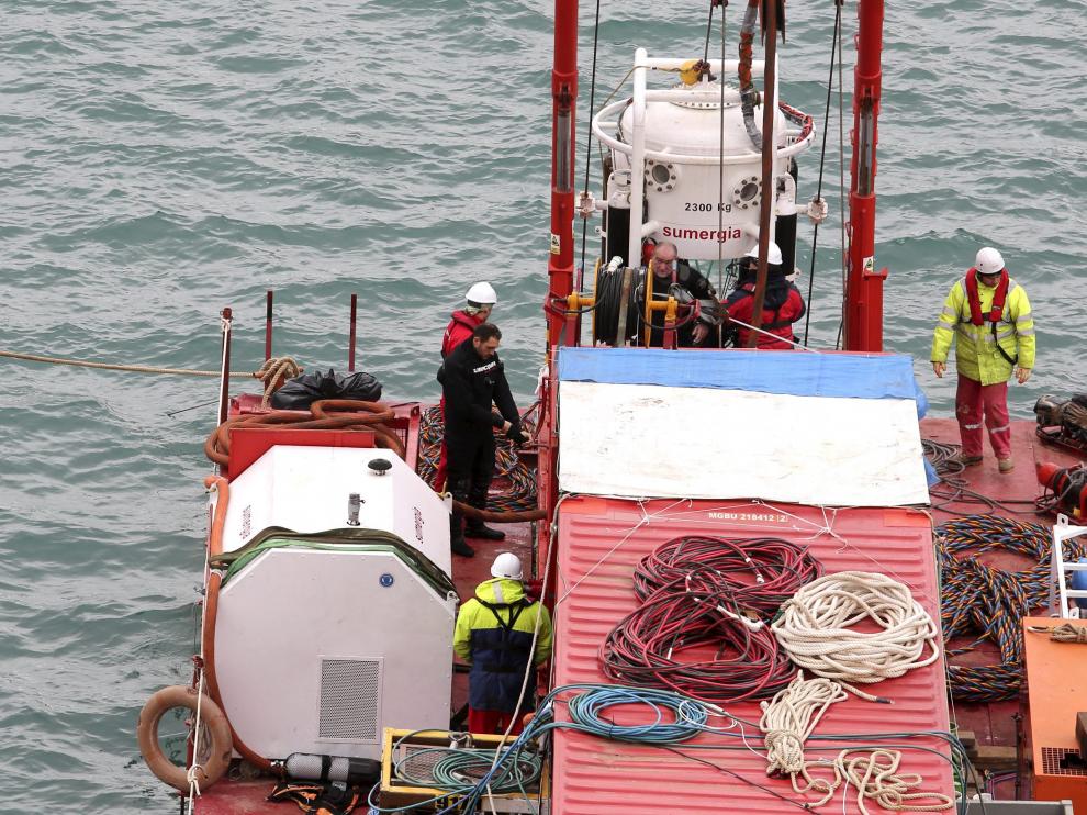 Los submarinistas salen de la campana tras izarla a una plataforma instalada en el embalse.