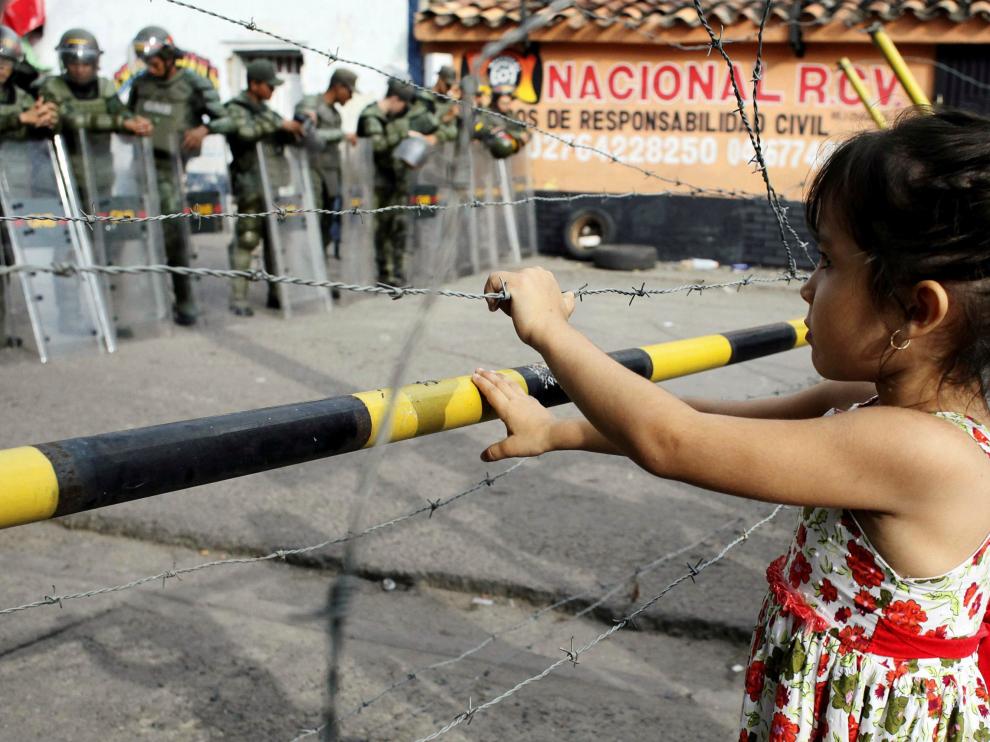 Una niña frente a una verja fronteriza entre Colombia y Venezuela