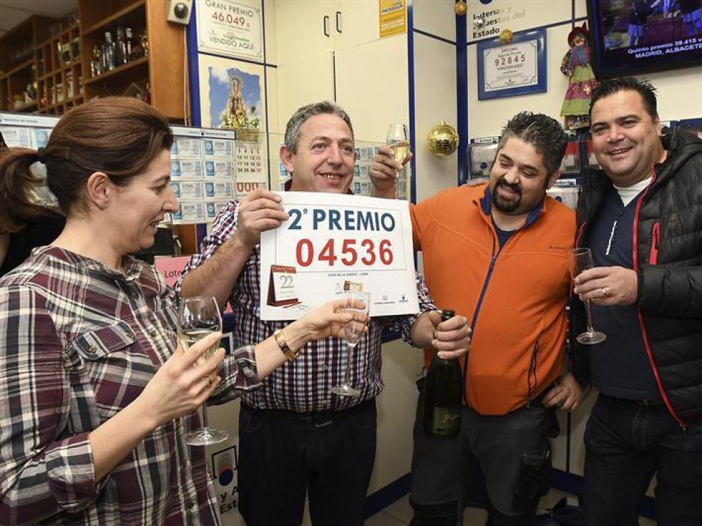 Manuel Martínez (2ºi), propietario del Café de la Suerte de León, y el agraciado Roberto Raposo (2d), celebran en el interior del establecimiento el segundo premio