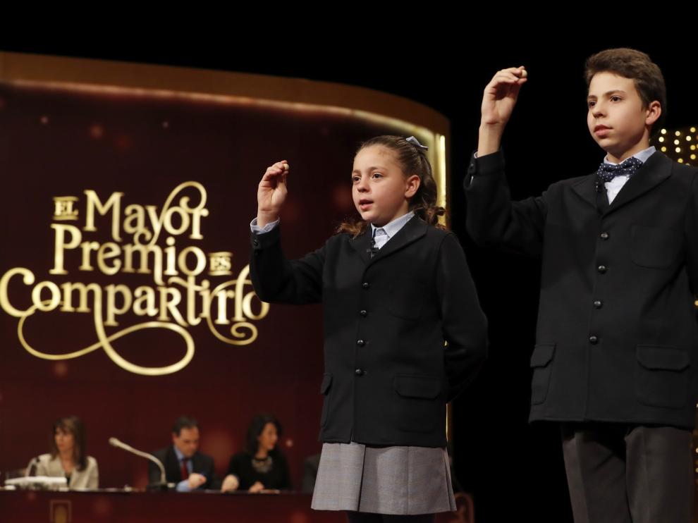 Los niños de San Ildefonso muestran el número que corresponde a uno de los quintos premios.