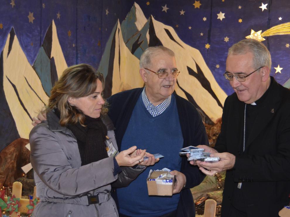 Raúl Revilla, capellán del Centro Penitenciario de Zuera -en el centro de la imagen-, coordina la entrega de las tarjetas telefónicas junto a una voluntaria y monseñor Pérez Pueyo.