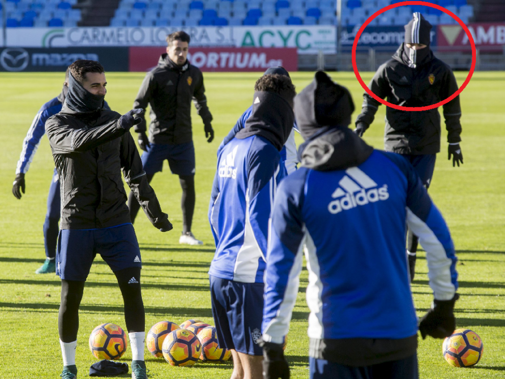 Popa, al que solo se le ven los ojos entre el gorro y la braga de cuello con los que siempre se entrena en las últimas semanas (arriba, a la derecha, dentro del círculo rojo), durante el inicio del entrenamiento de este jueves en La Romareda.
