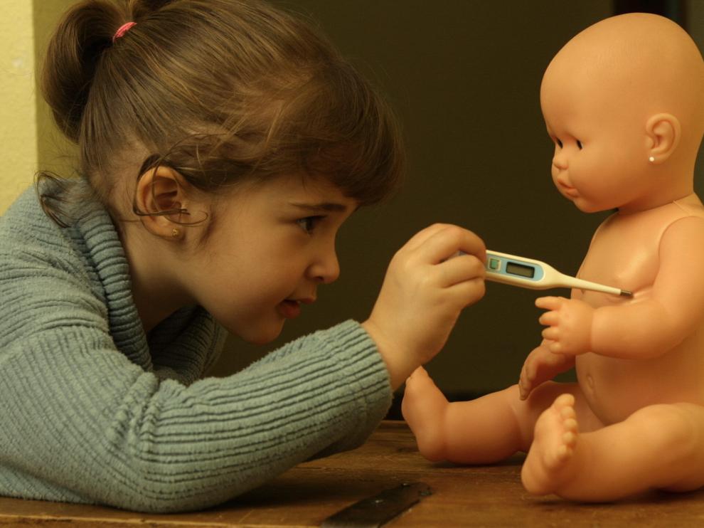 Una niña toma la temperatura a su muñeco.