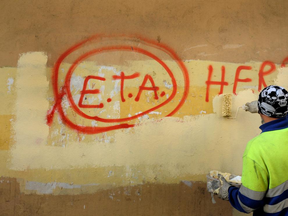 Un operario borra una pintada sobre ETA.