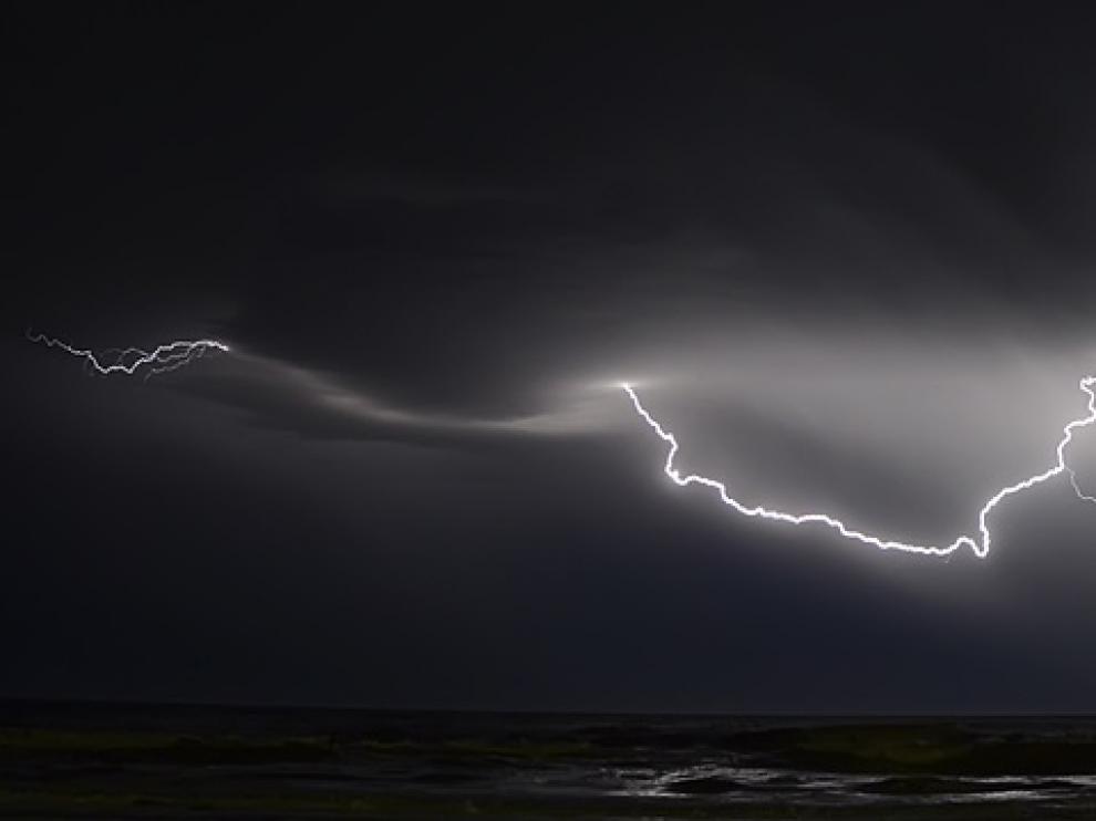 Una relámpago ilumina el mar en mitad de la noche.