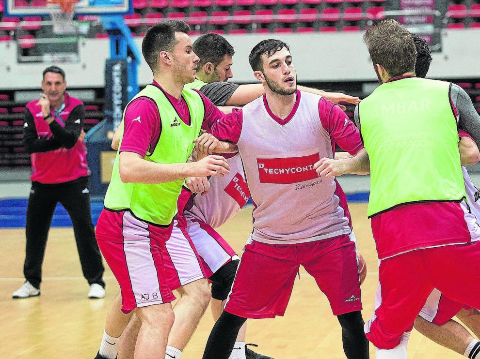 El base Sergi García, en el centro, rodeado de un grupo de compañeros, ante la mirada del técnico Luis Guil, al fondo.