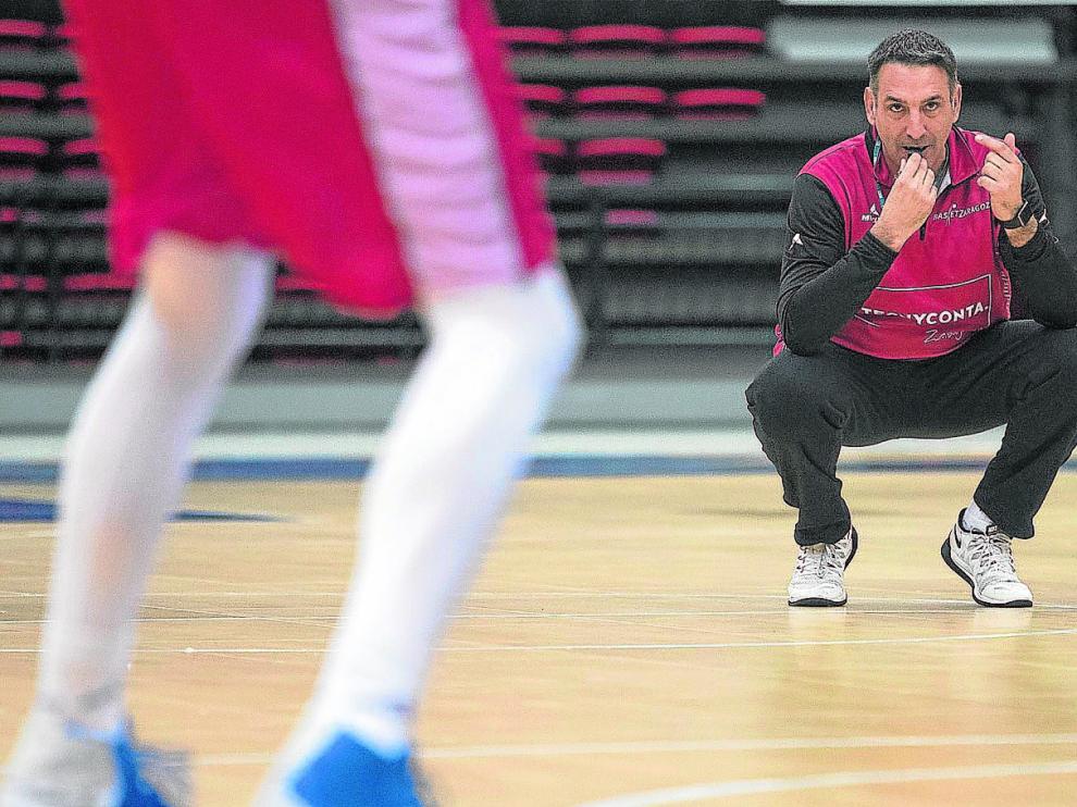 El entrenador Luis Guil, agachado y con el silbato en la boca, observa los movimientos de sus jugadores durante un entrenamiento.