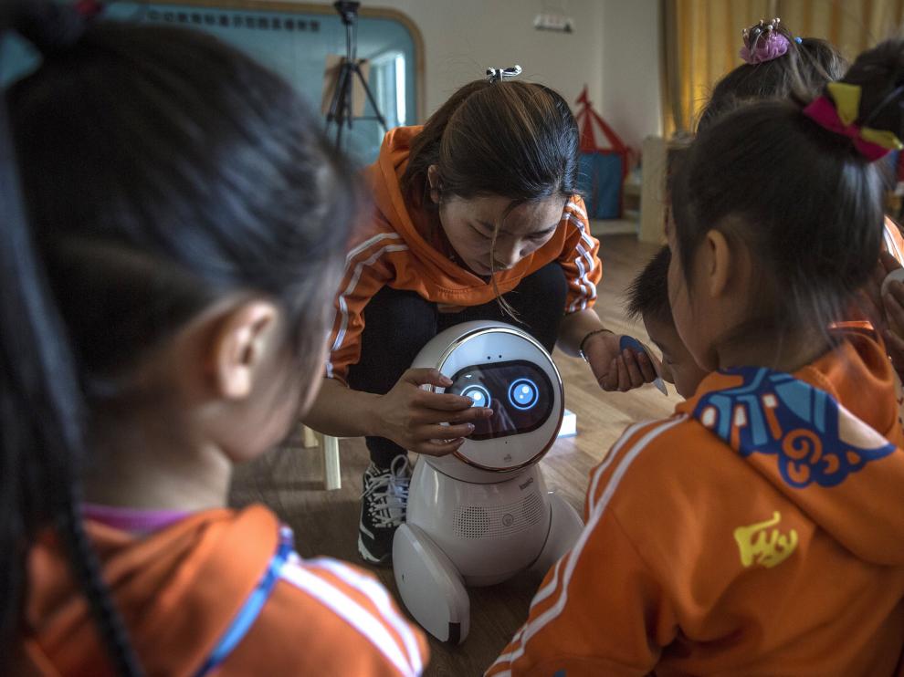 Los pequeños de una guardería China, junto al robot que les da clase