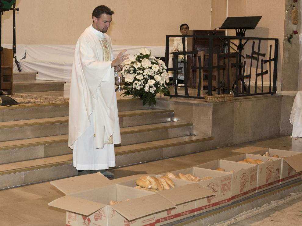 El párroco de Santa Rita, bendiciendo el pan que se entregó tras la misa.