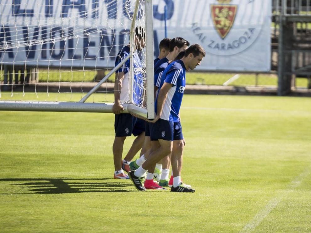 Varios jugadores del Real Zaragoza trasladan una portería móvil al inicio del entrenamiento.