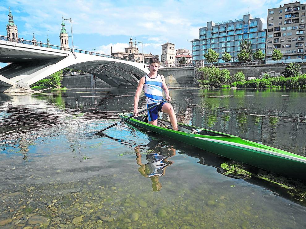 Bruno Herrero posa con los colores del CNHelios, sobre su embarcación, en el río Ebro de Zaragoza.
