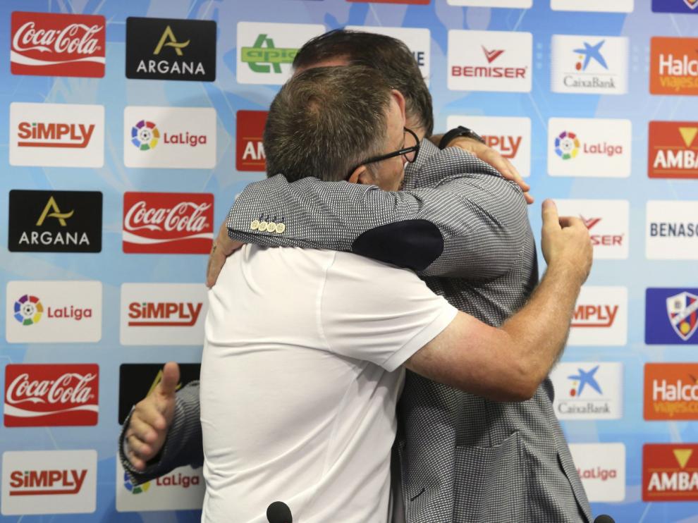 Juan Antonio Anquela, de blanco, se abraza con el presidente de la SD Huesca, Agustín Lasasosa.
