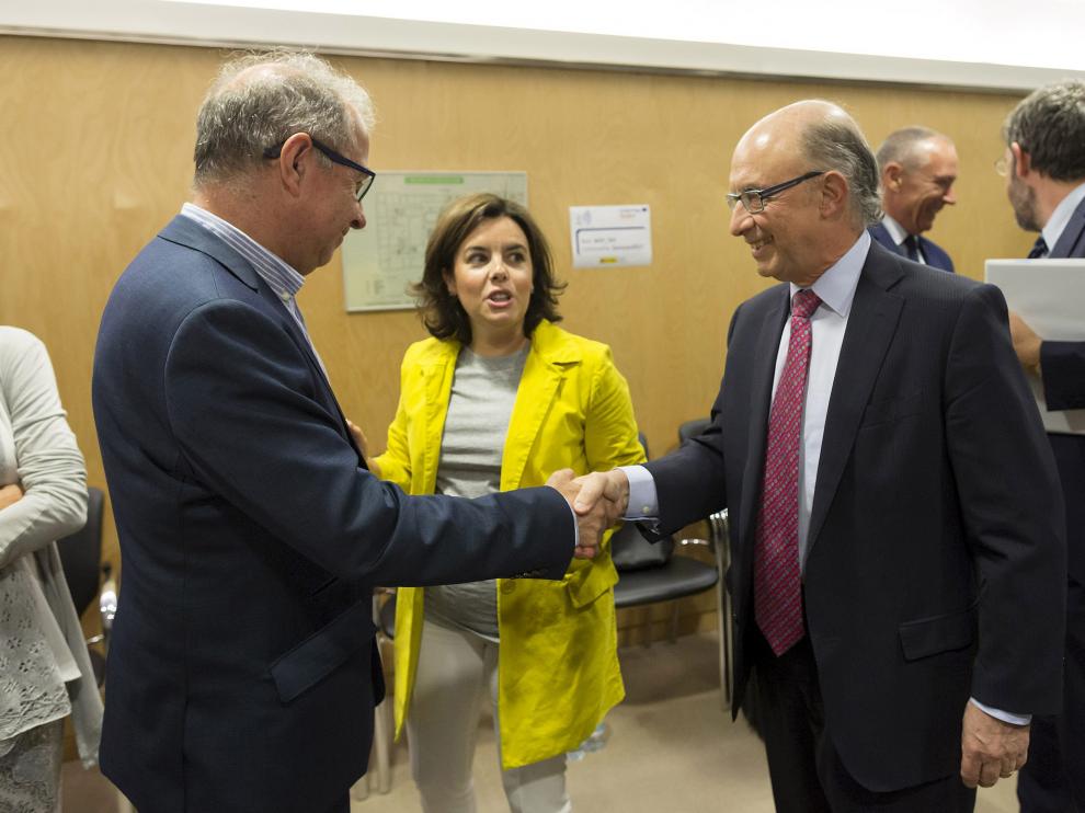 El consejero Gimeno saluda al ministro Montoro ante la vicepresidenta Saenz de Santamaría, este jueves.