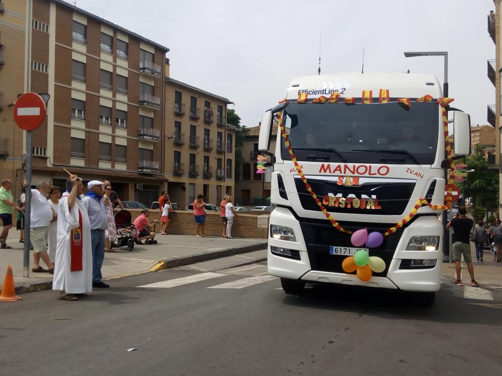 El párroco lanzando agua bendita a uno de los camiones que ha participado en el desfile.
