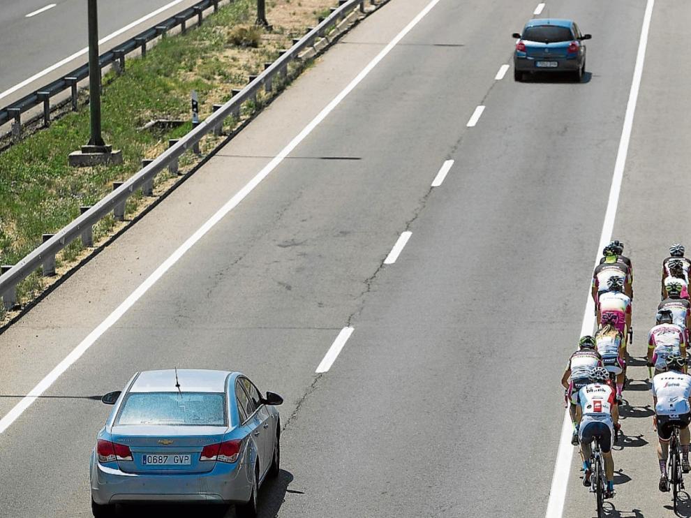 Un grupo de ciclistas circula por la carretera de Valencia mientras un vehículo adelanta correctamente.