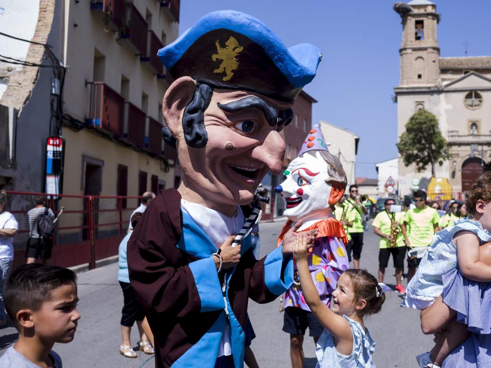 Una niña da la mano al cabezudo mientras su hermana, en brazos, llora asustada.