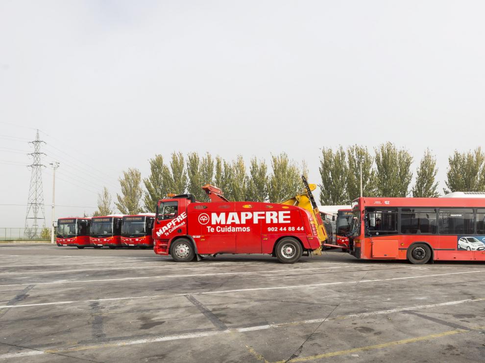 Una grúa con un autobús averiado pasa por delante de los once nuevos vehículos que se incorporaron a la flota el pasado mes de noviembre.