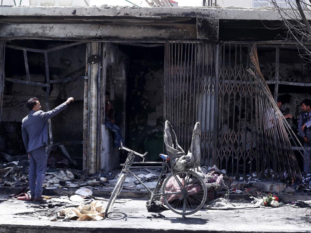 Afganos comprueban los daños en un establecimiento destrozado como consecuencia del atentado terrorista perpetrado este martes en Kabul.