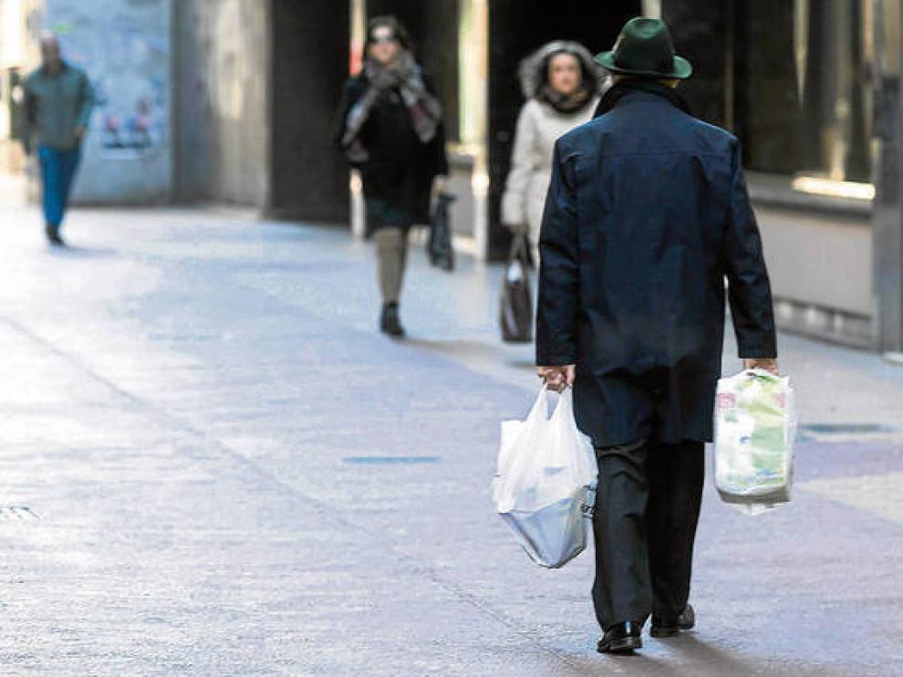 Un transeúnte pasea por Zaragoza con dos bolsas de plástico.
