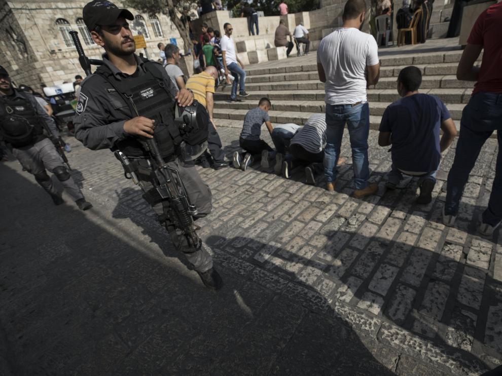 Un militar israelí patrulla mientras varios palestinos rezan fuera de la Puerta de los Leones, el acceso principal al complejo en el que se encuentra la Mezquita de Al Aqsa en Jerusalén (Israel) hoy, 24 de julio del 2017. Siguen los enfrentamientos diarios entre palestinos y fuerzas de seguridad israelíes por la instalación de nuevas medidas de seguridad en torno a la Explanada de las Mezquitas, tras el ataque mortal el pasado día 14 en el que murieron dos policías y sus tres atacantes.