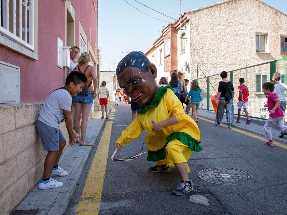 Un cabezudo acorrala a un niño que se ríe al esquivar el azote.