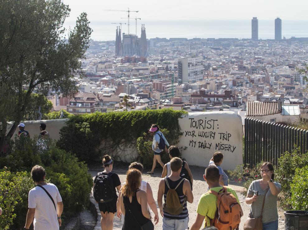 Un grupo de turistas pasea por los alrededores del Parque Guell de Barcelona, donde últimamente ha aparecido pintadas contrarias al turismo masificado.