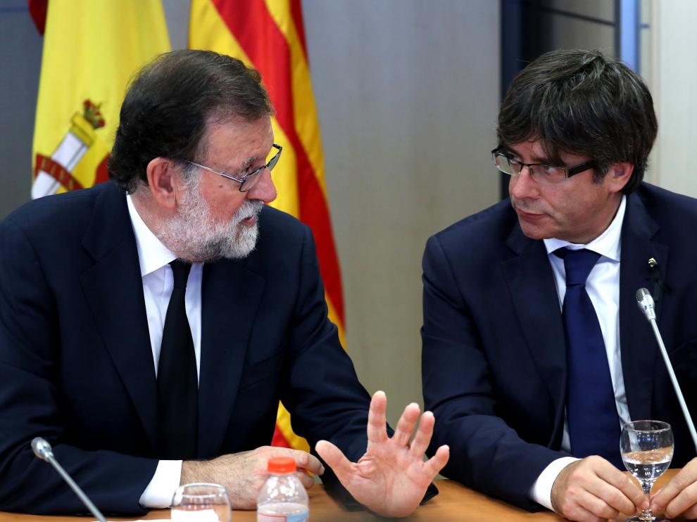 El presidente del Gobierno, Mariano Rajoy,iz., y el presidente de la Generalitat de Cataluña, Carles Puigdemont,d., conversan durante la reunión del gabinete de crisis celebrado