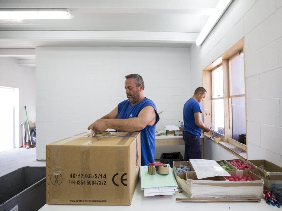 Ángel y Marius preparan carcasas en una caseta de montaje con ventanas protegidas.