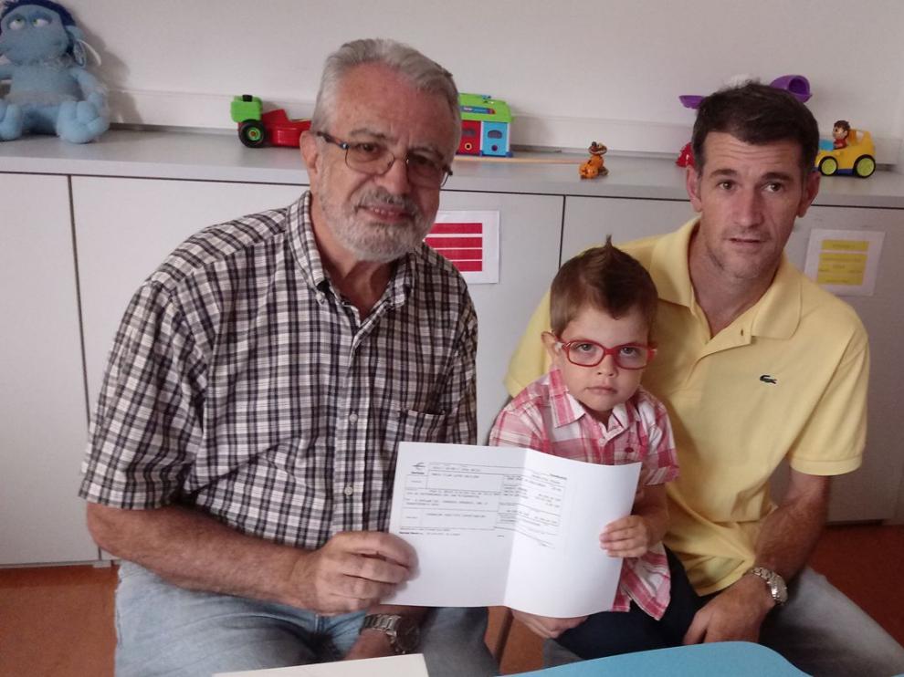 El investigador Julio Montoya, a la izquierda, recibe la donación de esta familia de Ariza de la mano del pequeño Javier, quien padece el raro síndrome de Pearson.