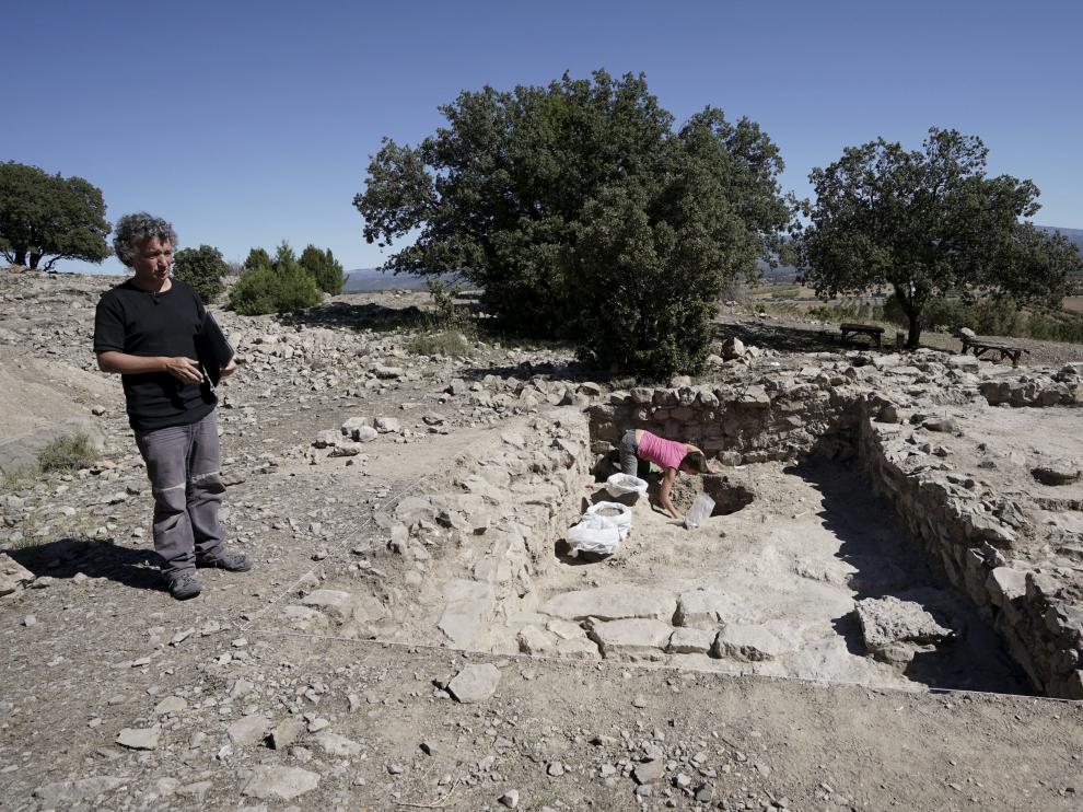 Julián Ortega explica las características del yacimiento mientras una arqueóloga excava un silo.