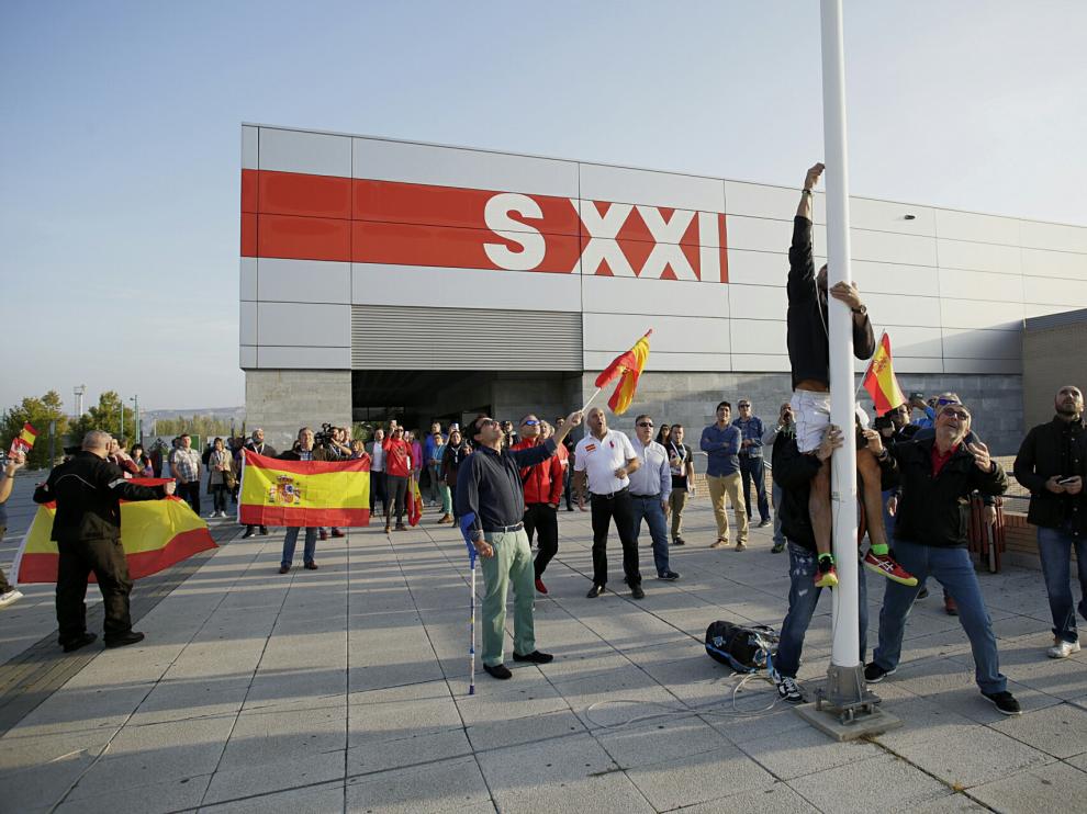 Varias personas han izado la bandera española a las puertas del pabellón siglo XXI.