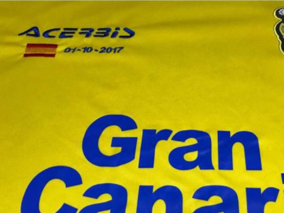 Detalle del frontal de la camiseta especial de la UD Las Palmas para jugar esta tarde del domingo en el Camp Nou ante el FC Barcelona: la novedad es la bandera de España bordada, con la fecha del 1-O.