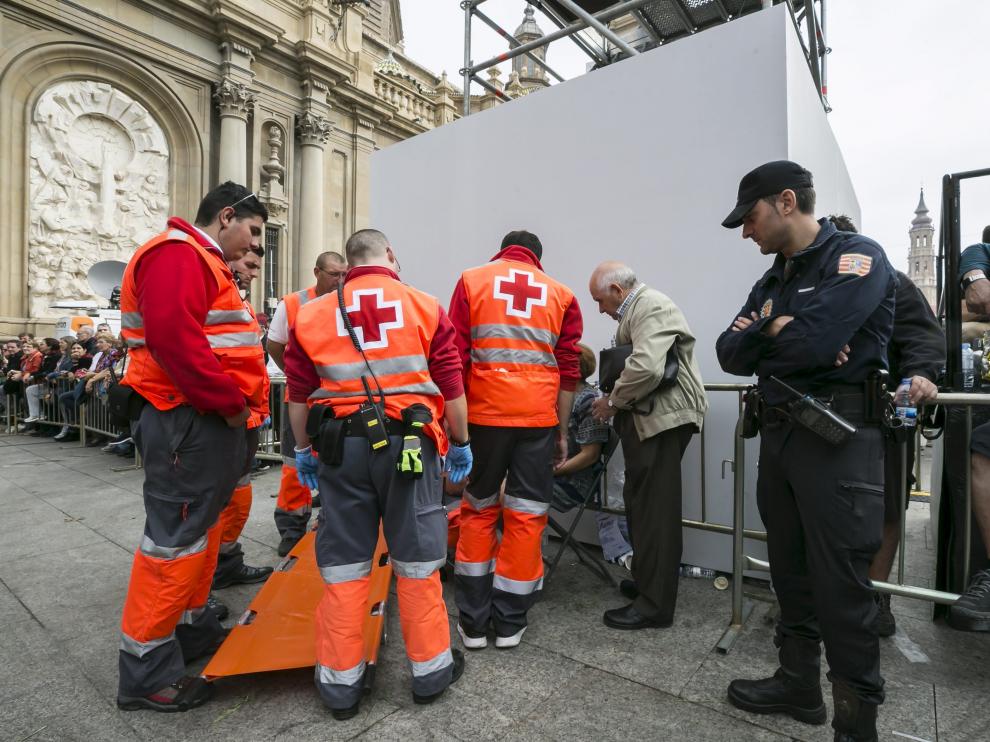 Varios voluntarios de Cruz Roja atienden a una persona durante la Ofrenda de Flores.