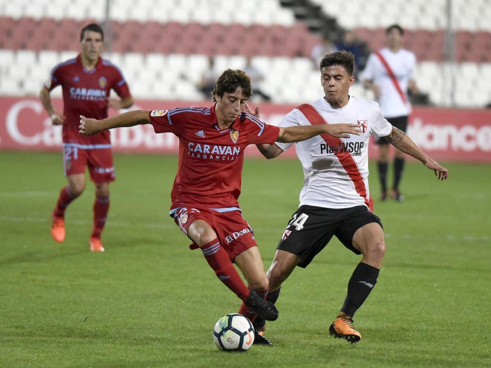 Julián Delmás avanza con la pelota ante la oposición de Felipe Carballo.