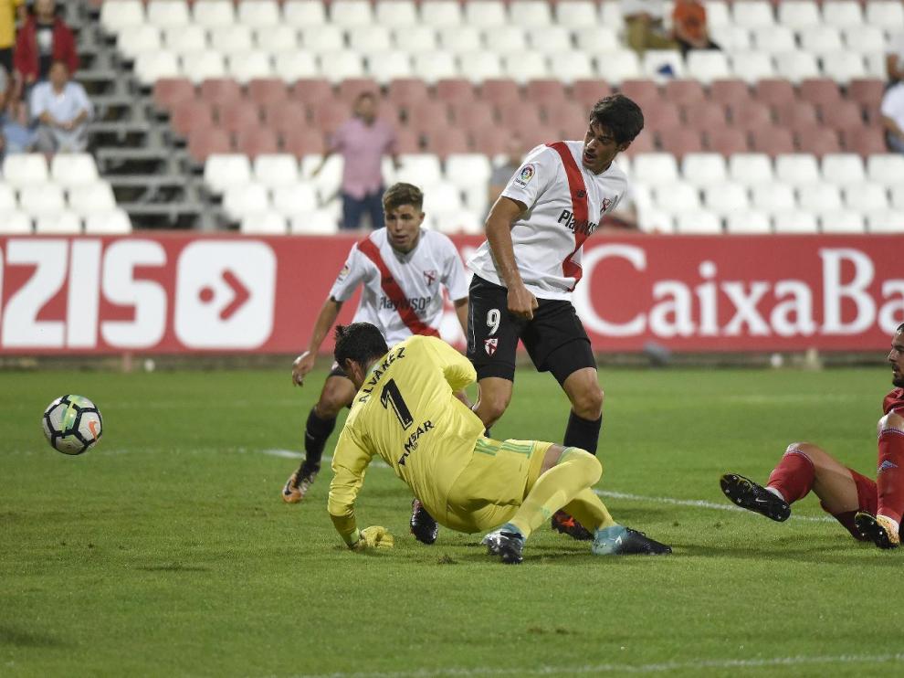 Verdasca y Cristian Álvarez por los suelos en el momento en el que Carlos Fernández, de rebote y de tacón, se aprovecha para anotar el 1-0 a favor del Sevilla Atlético.