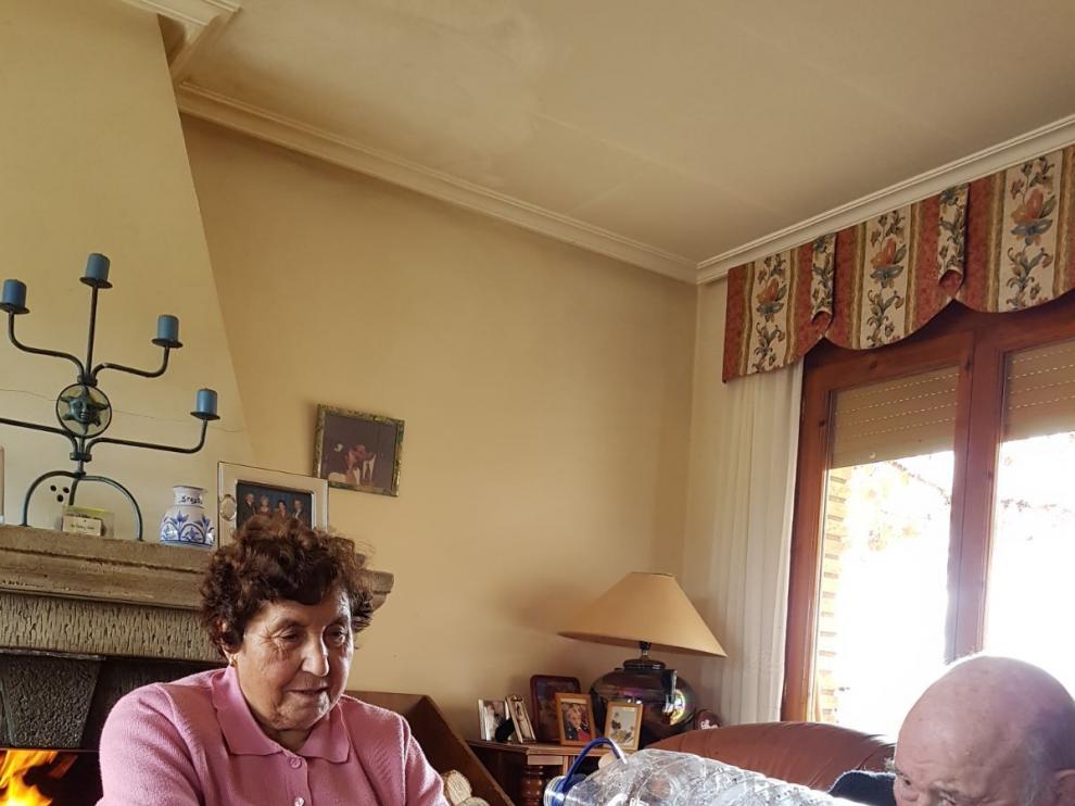 Rafaela Blas y Emiliano Sebastián rellenan una botella de una garrafa de agua.