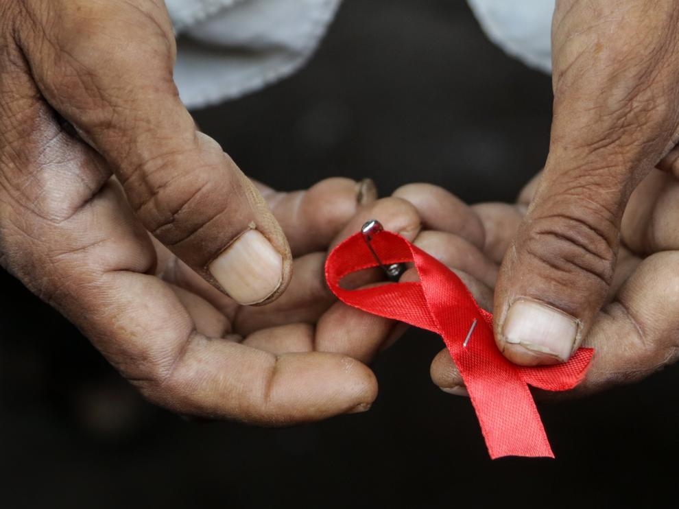 Un hombre sujeta un lazo rojo, símbolo de la lucha contra el sida.