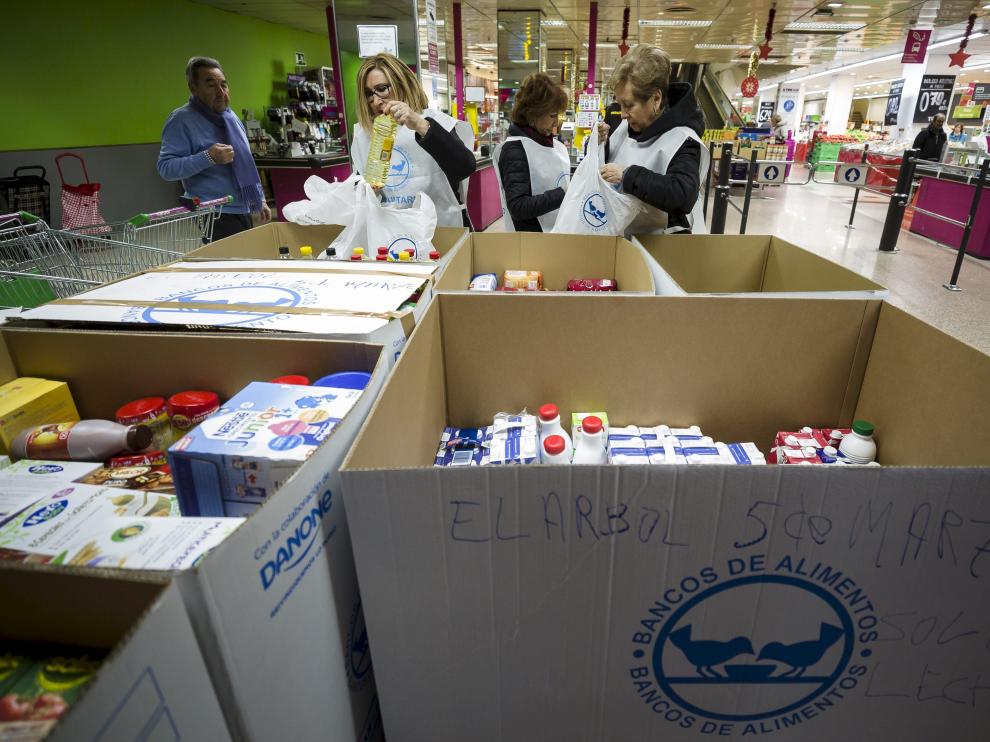 Aurelio Forcano, Isabel Gargallo, Araceli Giral y Merche García, todos ellos voluntarios, clasifican los alimentos.