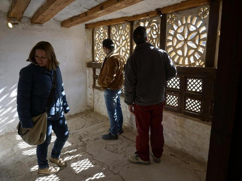 Un grupo de turistas visita la celda de la superiora del convento de Mirambel ante el mirador con celosía